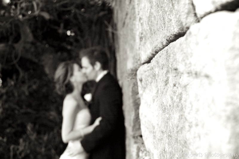 B&W bride and groom at sandstone wall - wedding photography